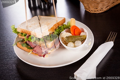 Image of Delicious pastrami club sandwich and pickles