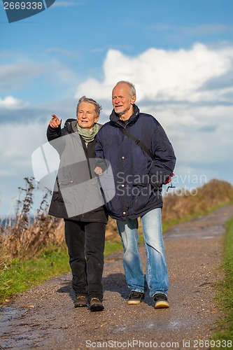 Image of happy elderly senior couple walking on beach