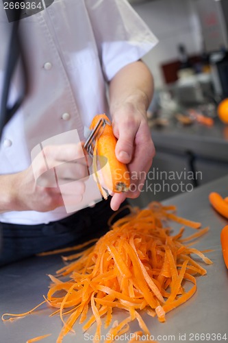Image of Chef in uniform preparing fresh carrot batons