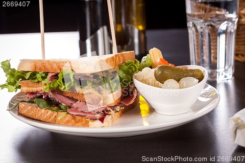 Image of Delicious pastrami club sandwich and pickles