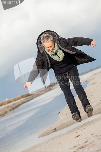 Image of Happy senior woman frolicking on the beach