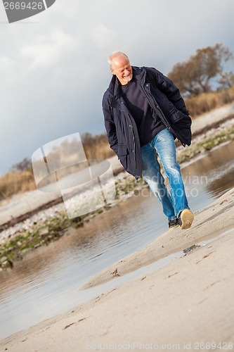 Image of Elderly energetic man running along a beach