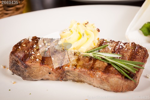 Image of Grilled beef steak topped with butter and rosemary