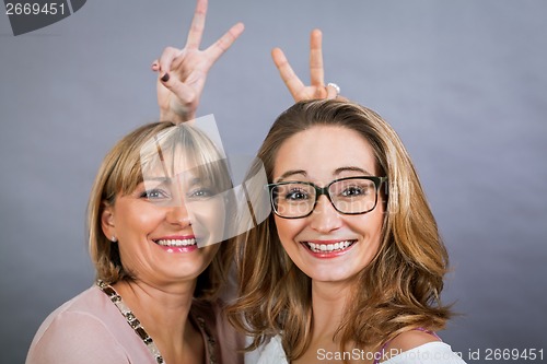 Image of smiling middle-aged young mother and daughter