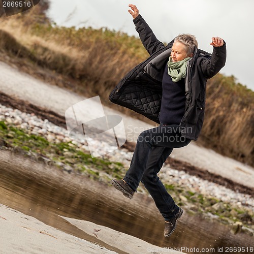 Image of Happy senior woman frolicking on the beach