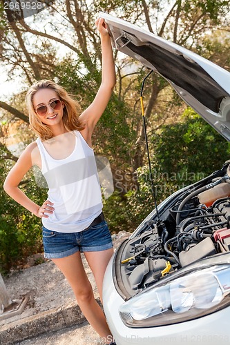 Image of Woman inspecting her car engine after a breakdown