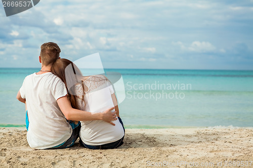 Image of romantic young couple sitting on the beach in summer