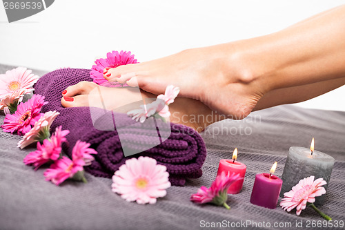 Image of Bare feet of a woman surrounded by flowers