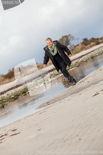 Image of Happy senior woman frolicking on the beach