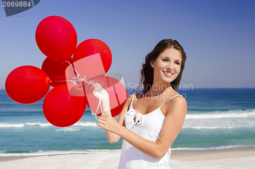 Image of Beautiful girl holding red ballons