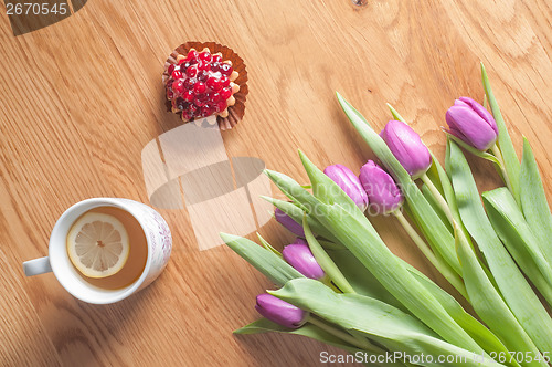 Image of Violet tulips, cake and tea on the wood