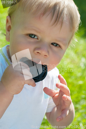 Image of Cute baby boy holding lens cover on his mouth
