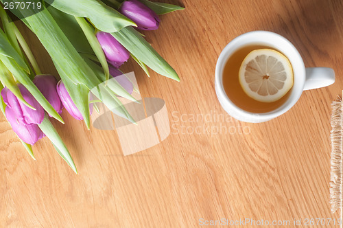 Image of Violet tulips on the wood and tea, top view