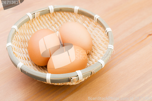Image of Egg in basket with wooden background