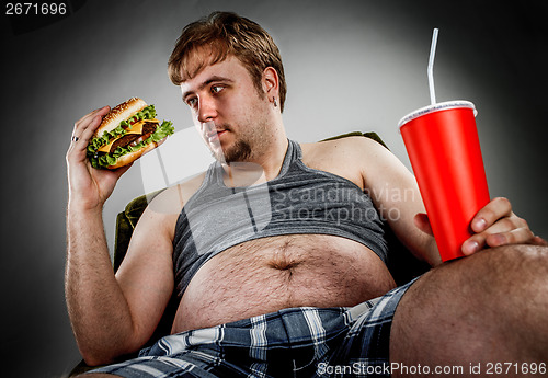 Image of Fat man eating hamburger