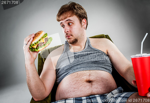 Image of Fat man eating hamburger