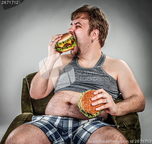 Image of Fat man eating hamburger