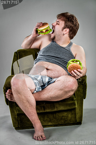 Image of Fat man eating hamburger