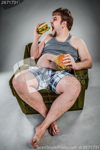 Image of Fat man eating hamburger