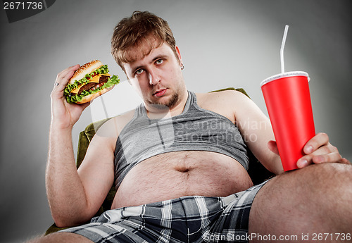 Image of Fat man eating hamburger