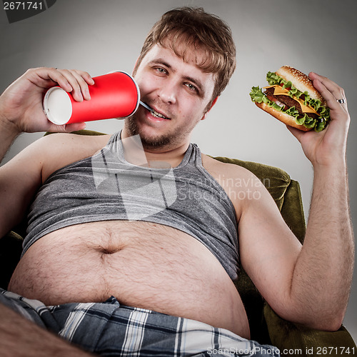 Image of Fat man eating hamburger