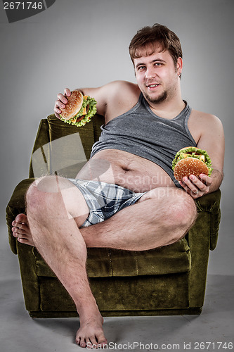 Image of Fat man eating hamburger