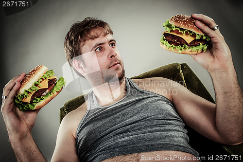 Image of Fat man eating hamburger