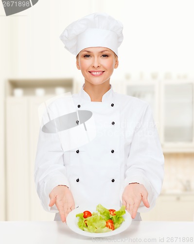 Image of smiling female chef with salad on plate