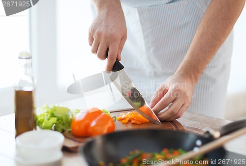 Image of close up of male hand cutting pepper on board