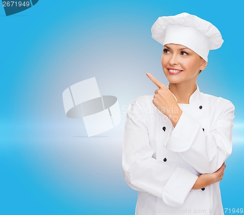 Image of smiling female chef pointing finger to sonething