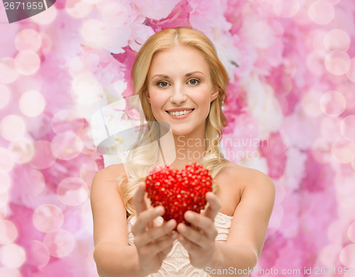 Image of smiling woman giving small red heart