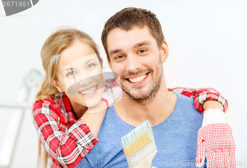 Image of smiling couple covered with paint with paint brush