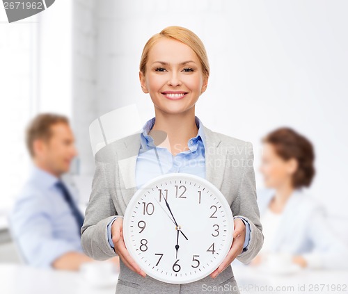 Image of smiling businesswoman with wall clock