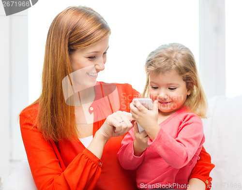 Image of happy mother and daughter with smartphone at home