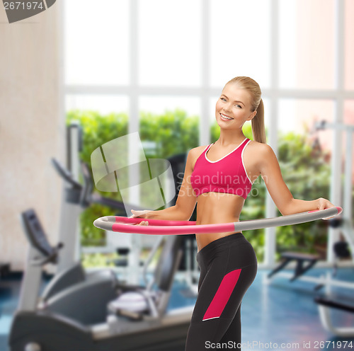 Image of young sporty woman with hula hoop at gym