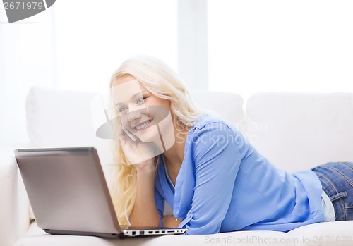 Image of smiling woman with smartphone and laptop at home