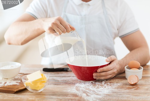 Image of close up of male hand pouring milk in bowl