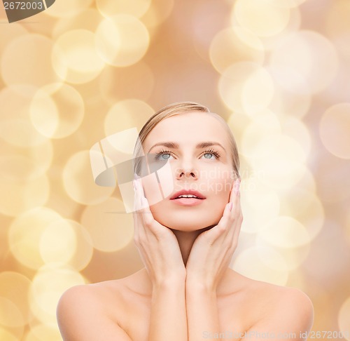 Image of beautiful woman touching her face and looking up