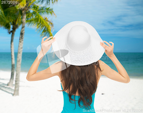 Image of woman sitting in swimsuit with hat