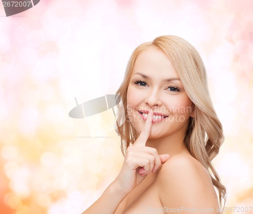 Image of beautiful young woman pointing finger to lips