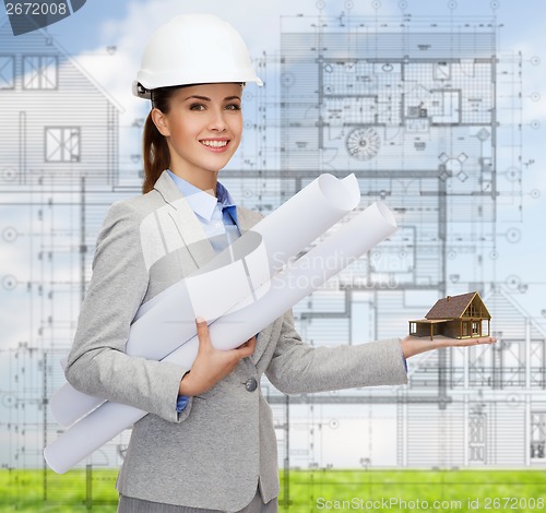 Image of smiling architect in white helmet with blueprints