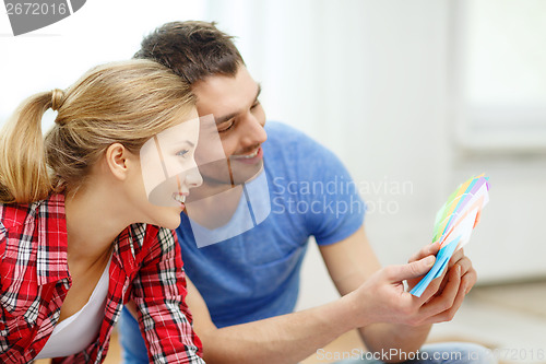 Image of smiling couple looking at color samples at home