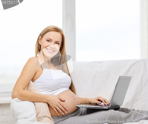 Image of smiling pregnant woman with laptop computer