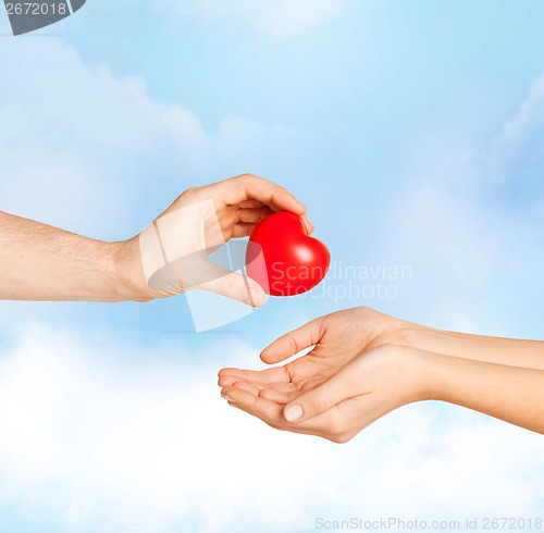 Image of man hand giving red heart to woman