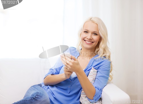 Image of smiling woman with smartphone at home