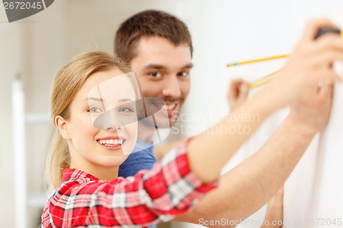 Image of smiling couple measuring wall