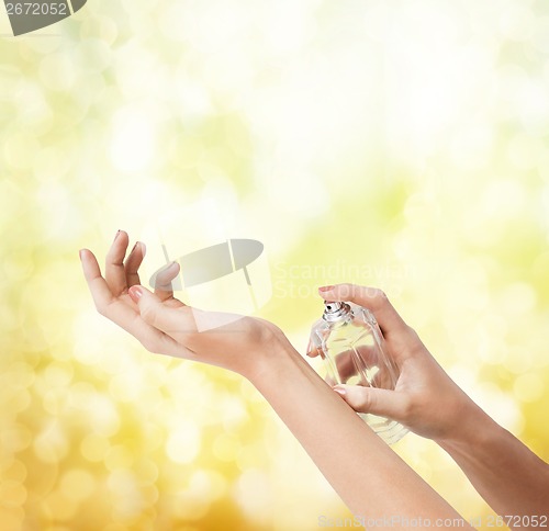 Image of woman hands spraying perfume