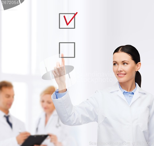 Image of smiling female doctor pointing checkbox