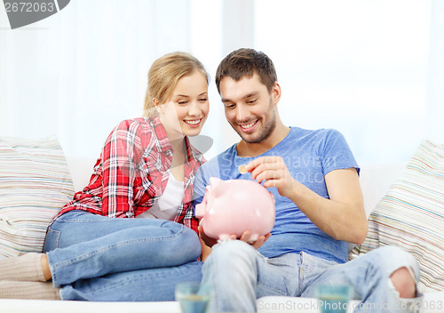 Image of smiling couple with piggybank sitting on sofa