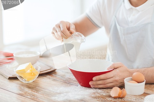 Image of close up of male hand pouring milk in bowl